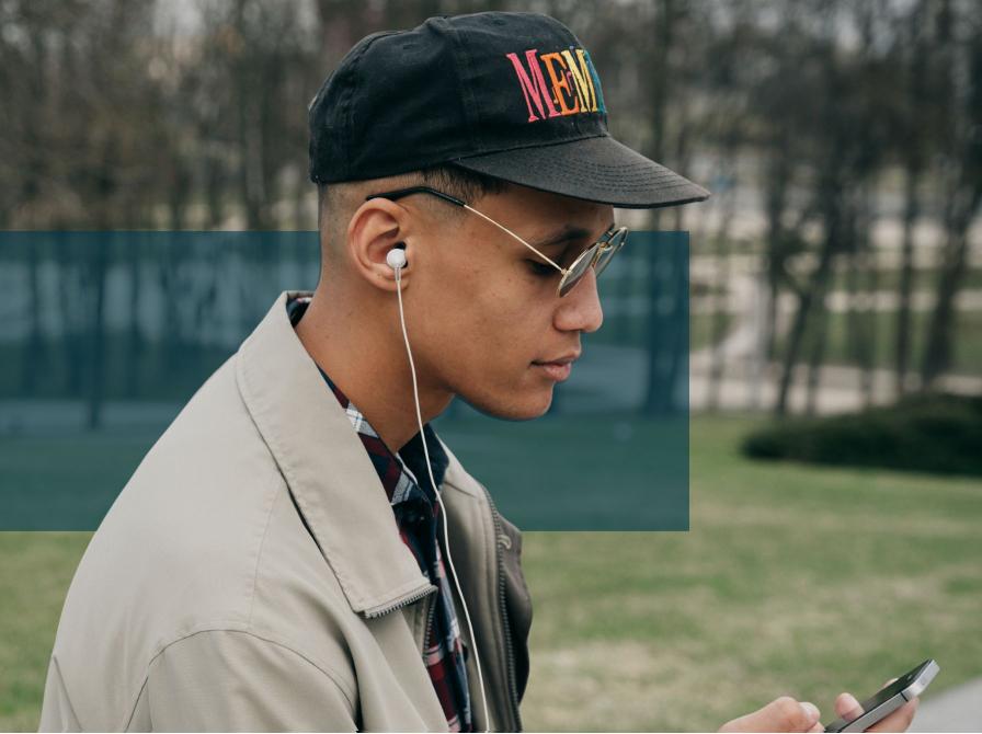 En mand har AirPods i ørerne og ser ned på sin telefon.